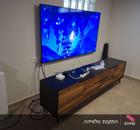 טלוויזיה תלויה על הקיר עם כבלים ומכשירים חשמליים